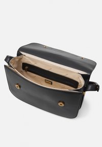 Černá kožená kabelka se zlatým kováním, zavíráním na klopu a béžovou textilní podšívkou. Obsahuje vnitřní kapsu na zip a logo značky.