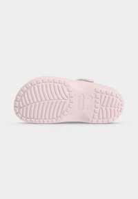 Σόλα ενός ανοιχτό ροζ clog Crocs που δείχνει το υφή μοτίβο πέλματος και τις ενδείξεις μεγέθους σε απλό λευκό φόντο.