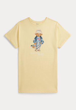 Tricou galben cu mâneci scurte cu un urs purtând o pălărie tip găleată, o geacă din denim, pantaloni cu dungi, sandale și care ține un coș cu flori.