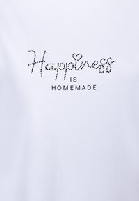 Weißes Baumwoll-T-Shirt mit schwarzem Strassstein-Text, der in geschwungener Schrift "Happiness IS Homemade" mit einem Herzakzent liest.