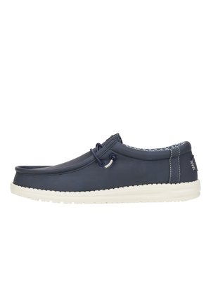 Zapato azul marino de cuero sin cordones con suela de goma blanca, punta redonda y cordones decorativos. Forro texturizado y detalles de costura sutiles.