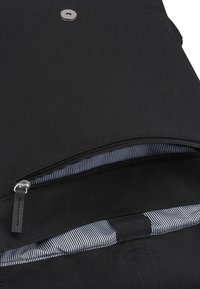 Fekete textil táska cipzárral az elején. A bélés csíkos mintájú. Ezüst gomb részletekkel és fekete pánt hurokkal rendelkezik.