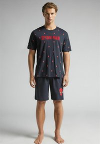 Schwarzes Baumwoll-T-Shirt mit rotem C1SPIDER-MAND-Text und kleinen Spinnen-Symbolen; passende Shorts mit rotem Spider-Man-Emblem am rechten Bein.