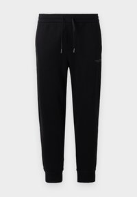 Sorte joggebukser laget av bomullsblanding, med elastisk midjebånd og snor, oppbrettede ankler, og et subtilt logotrykk på siden.