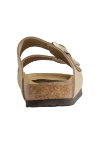 Sandale beige avec une semelle en liège, dotée de deux brides réglables et d'un talon plat. La tige a une texture lisse et des accents métalliques subtils.