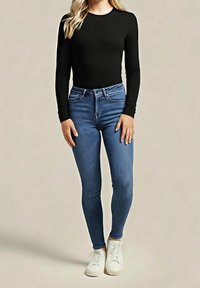 Top negro de manga larga combinado con jeans ajustados azules. Los jeans tienen cintura alta, cinco bolsillos, y se complementan con zapatillas blancas.