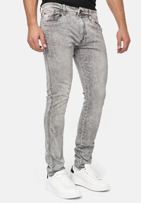 Vaqueros de denim gris claro con un acabado deslavado, de corte slim, y costuras en contraste en los bolsillos, combinados con zapatillas blancas.