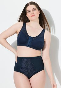 Marine blauw beha en hoog opgesneden slipset met kant overdekte cups en decoratieve borduursels op de slip, textuur materiaal en verstelbare bandjes.