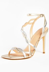 Sandal con tacco alto in oro e argento, dotata di cinturini intrecciati, punta quadrata e sottile cinghietta alla caviglia, caratterizzata da una finitura metallica e una texture liscia.