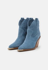 Botas de tobillo de ante azul con puntera puntiaguda y tacones de cuña. Presentan costuras decorativas y un acento plateado en la punta.