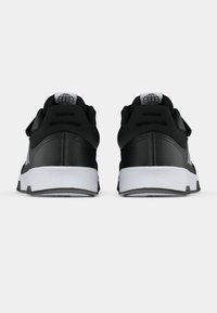 Par tenisica crne boje s bijelim potplatima, prikazane s leđa, koje pokazuju uložene ovratnike i globus logo na petnim oznakama.