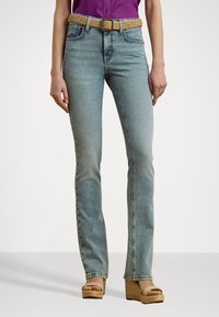 Lyseblå denimjeans med slank passform, med et vevd brunt belte og frontlommer. Brukt med brune kilehæl sandaler.