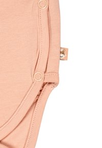 Light pink baby onesie with snap buttons and a small fabric tag featuring a smiling animal face.