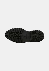 Semelle de chaussure en caoutchouc noir avec un motif de texture antidérapant, comportant des sections surélevées pour la traction et des détails de logo. Section centrale lisse.