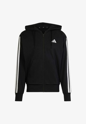 Svart hettegenser med glidelås laget av myk fabric, med hvite striper på ermene og en liten hvit logo på brystlommen.