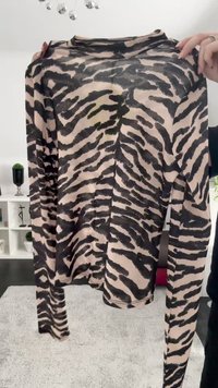 Maglia a maniche lunghe aderente color beige con stampa a strisce di tigre nera. Tessuto morbido, scollatura rotonda e cuciture minime visibili.