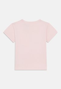 Κοντομάνικο μπλουζάκι σε ανοιχτό ροζ, κατασκευασμένο από απαλό βαμβάκι. Απλός, χωρίς διακοσμήσεις σχεδιασμός με στρογγυλή λαιμόκοψη και ραμμένα τελειώματα.