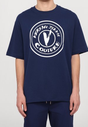 Granatowa bawełniana koszulka z okrągłym białym logo z napisem "VERSACE JEANS COUTURE" oraz wyraźnie stylizowaną literą "V."