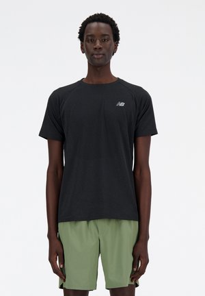Black short-sleeve athletic shirt with mesh texture and New Balance logo, paired with green shorts. Simple, athletic fit design.