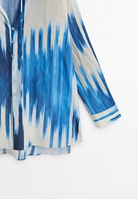 Kevyt kangas, sinivalkoinen liukuvärjätty kuvioitu napillinen paita, jossa rento leikkaus ja pitkät hihat.