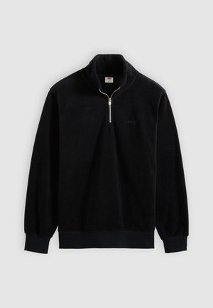 Fekete polár pulóver negyed cipzáras gallérral, bordázott mandzsettákkal és szegéllyel. Finom logó található a mellkason és puha anyagú.