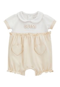 Mono blanco de manga corta con cuello redondo, bolsillos en forma de corazón en beige, cintura con volantes y logotipo "GUESS" bordado en beige.
