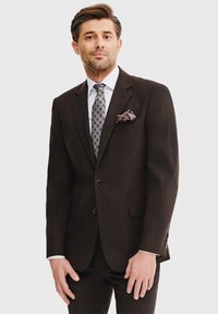 Ciemnobrązowy garnitur z dwoma guzikami, klapkami i bocznymi kieszeniami. Biała koszula i wzorzysty krawat, poszetka z kwiatowymi akcentami.