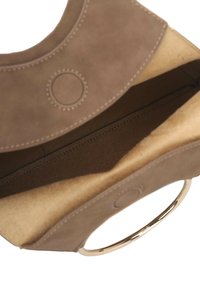 Interno di una borsa in camoscio marrone con una texture liscia, dettagli circolari e manico ad anello metallico. L'interno presenta una tasca piatta e cuciture.