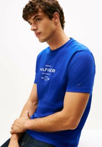 Royalblå kortærmet t-shirt lavet af bomuld, med hvid tekstlogo "TOMMY HILFIGER NEW YORK CITY" på forsiden og et lille logo på ærmet.