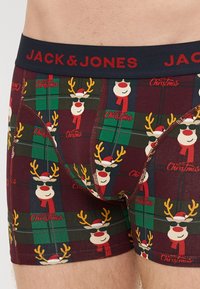 Men's boxers in dark red with a holiday reindeer pattern. Features a navy waistband with "JACK & JONES" logo, made of soft cotton blend fabric.