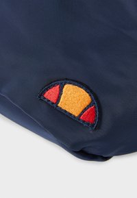 Borsa di tessuto blu navy con logo ricamato che presenta un design a mezzaluna nei colori arancione, rosso e giallo, accentuato da cuciture nere.