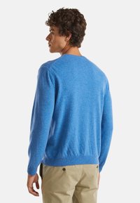 Niebieski sweter dzianinowy z okrągłym dekoltem, długimi rękawami i ściągaczami. Miękka tekstura, z minimalnymi detalami z tyłu.