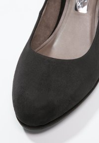 Pompe en daim noir avec un bout arrondi et une finition lisse et élégante. L'intérieur présente une texture contrastante subtile près de l'ouverture.