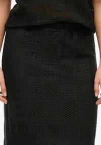Falda negra texturizada con un patrón en cuadrícula, que presenta detalles de tejido abierto. Fabricada con material liviano para una mejor transpirabilidad.