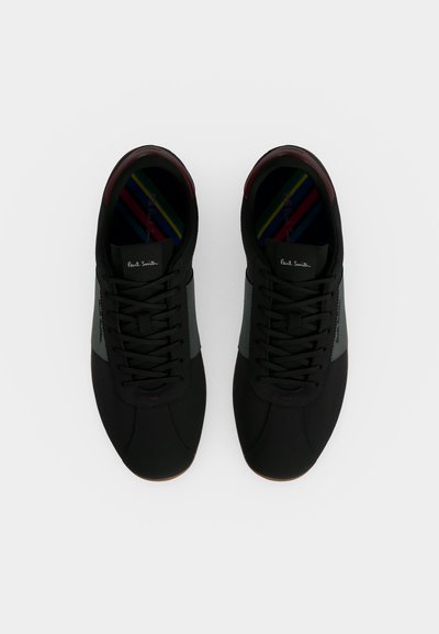 Paire de baskets noires à lacets avec panneaux latéraux gris et semelles intérieures rayées multicolores, vues de dessus sur fond blanc.