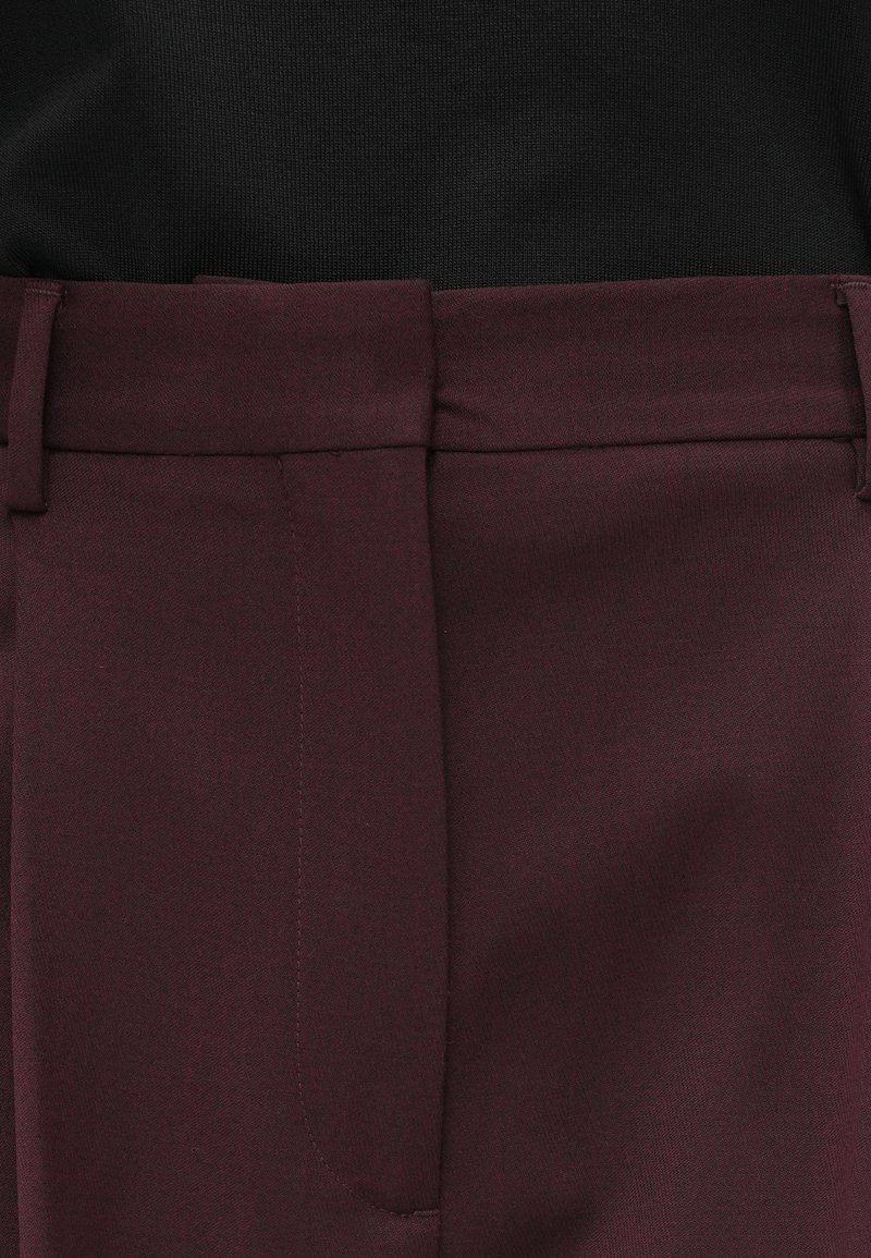 Burgundy tailored trousers with a smooth texture, featuring a flat front design, side pockets, and a polished waistband.