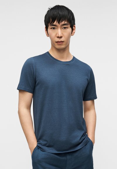 Μπλε κοντομάνικο T-shirt από απαλό, υφασμάτινο ύφασμα με στρογγυλή λαιμόκοψη και χαλαρή εφαρμογή, συνδυασμένο με παντελόνι σε παρόμοιο χρώμα.