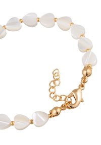 Aukso spalvos apyrankė su širdelės formos baltais karoliukais ir užsegimu. Lygi tekstūra su blizgiais akcentais ir reguliuojamu grandinėlės ilgimu.