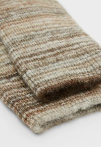 Écharpe en laine avec un motif texturé et multicolore dans des nuances de beige et de brun, présentant des rayures horizontales et une surface douce et duveteuse.