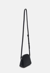 Borsa a tracolla nera con forma curvata, realizzata in materiale morbido, dotata di chiusura con zip e sottile tracolla regolabile.
