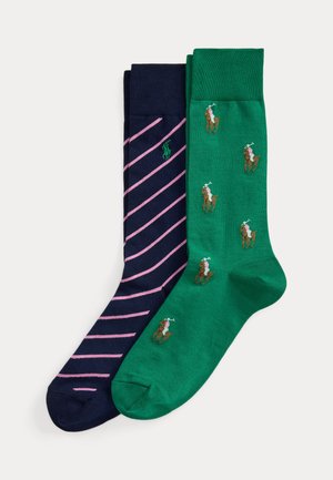 Une paire de chaussettes bleu foncé avec des rayures diagonales roses et un logo vert, et une paire de chaussettes vertes avec de petits motifs de joueurs de polo.