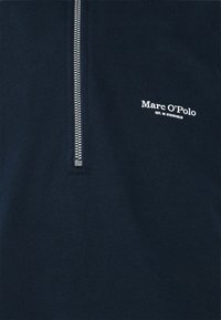 Felpa blu navy con zip in tessuto morbido, caratterizzata da una zip argentata e dal logo bianco "Marc O'Polo" ricamato sul davanti.