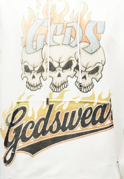 Kolm põlevat koljupilti sõna "Gcdswea" kohal, mis on kirjutatud julge, stiliseeritud musta kirjatüübiga, mida ümbritsevad kollased leegid, valgel kangapõhjal.