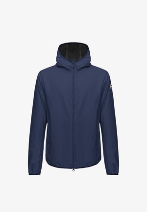 Veste légère à capuche bleu marine avec fermeture éclair intégrale à l'avant et écusson logo sur la manche gauche, conçue pour une utilisation en extérieur.