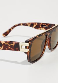 Ochelari de soare din tortoise cu lentile căprui, formă pătrată, accente din materiale metalice aurii și un detaliu de marcă pe braț. Material din plastic durabil.