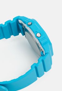 Orologio in silicone blu con cinturino testurizzato, bottoni metallici e retro argentato visibile. Presenta un design rettangolare e arrotondato.