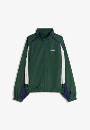 Groen jack met ritssluiting, witte meshpanelen, marineblauwe accenten, elastische manchetten en zoom. Voorzien van een logo op de borst en een kraag.