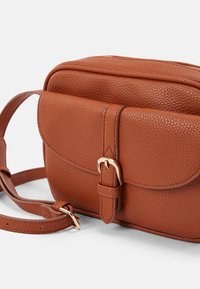 Borsa a tracolla in pelle marrone con texture, con patta frontale fissata da una cintura e una fibbia dorata, e tracolla regolabile.
