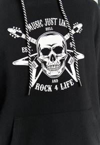 Sort hættetrøje med et fremtrædende hvidt kraniumgrafik, guitarer og tekst, der siger "Music Just Like Hell Established 91 og Rock 4 Life."