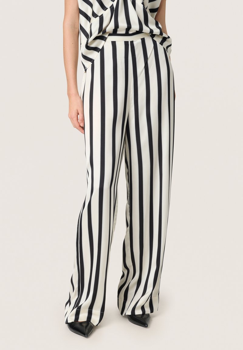 Pantaloni a gamba larga a righe bianche e nere realizzati in un tessuto leggero e liscio, dotati di una vita elastica e di una vestibilità comoda.